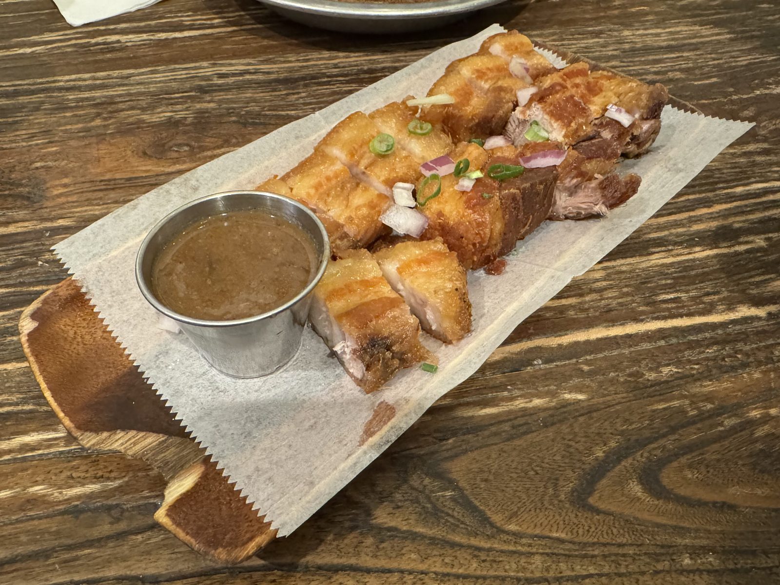 Sliced Lechon Kawali, crispy-skinned fried pork belly, served with a side of dipping sauce